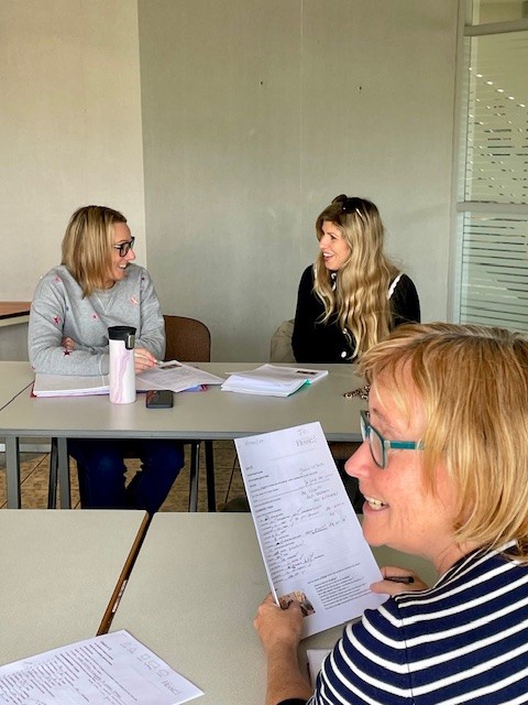 On voit un groupe de femmes qui suit un cours de français et qui semblent heureuses